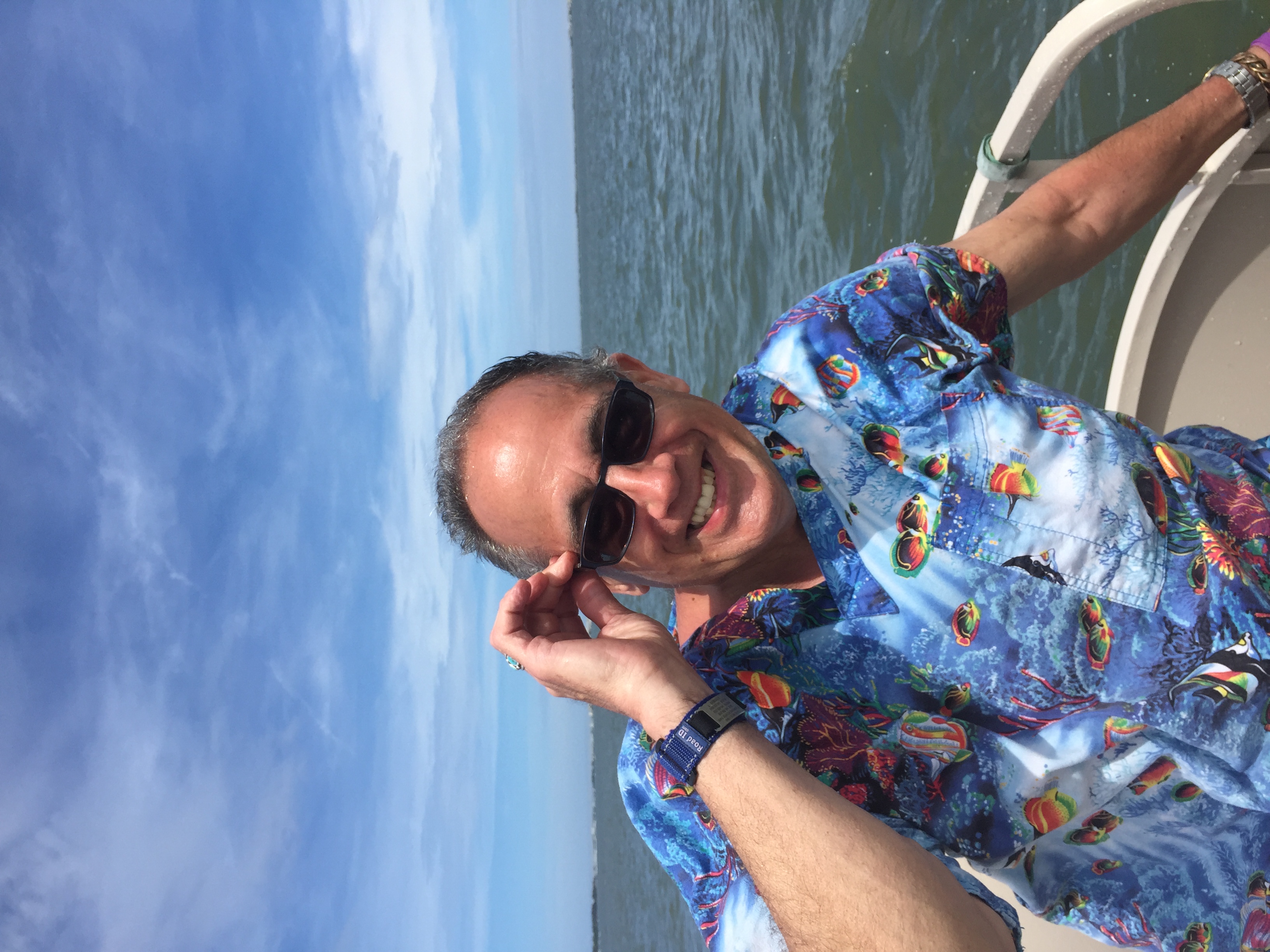 Dave smiling on a boat in a bright blue shirt